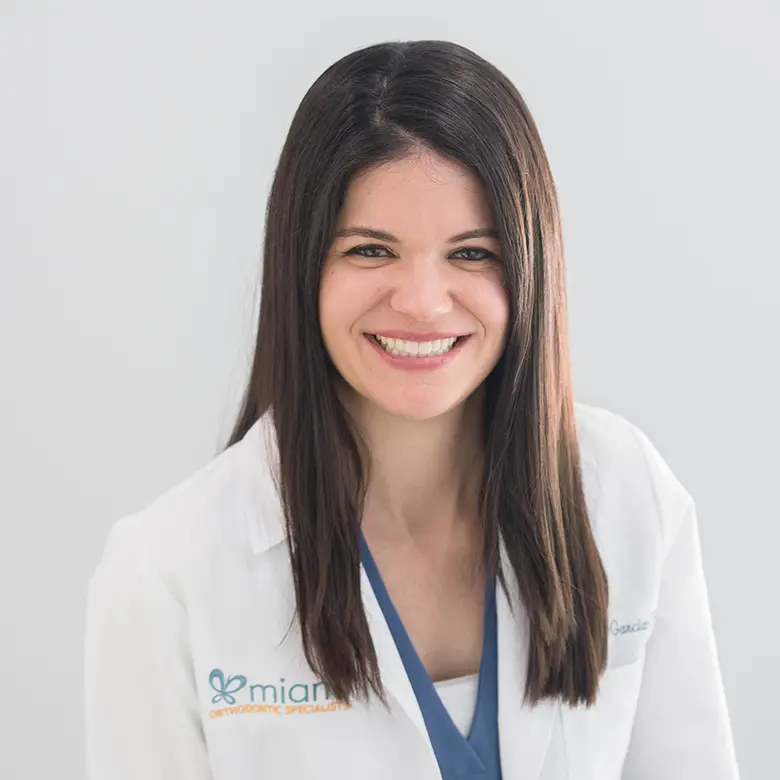 Dr. Carmen Garcia-Paul smiling in a white coat, representing Miami Orthodontic Specialists.