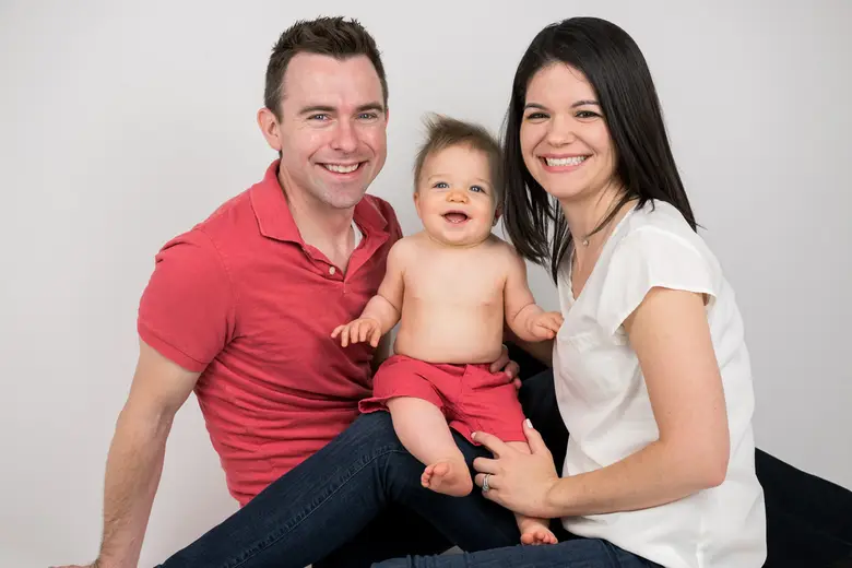 Smiling family portrait featuring Dr. Carmen Garcia-Paul with her husband and their baby.