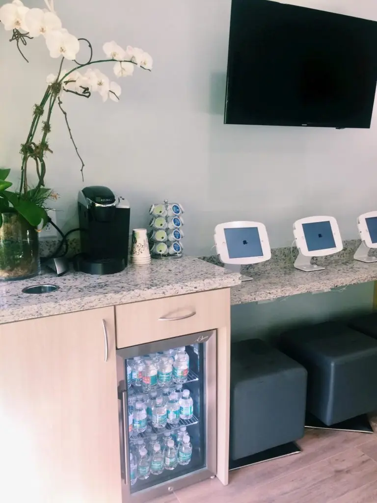 Modern orthodontic office waiting area featuring a coffee station, water cooler, and seating, designed for patient comfort at Miami Orthodontic Specialists.